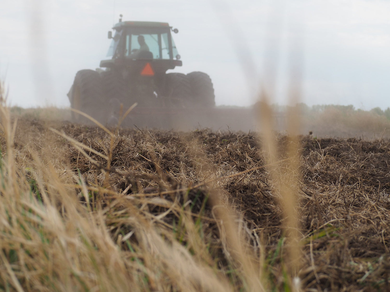 A tractor tilling a field for pollinator pastures